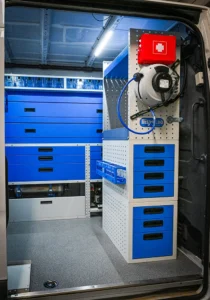 Side-door mobile mechanic van storage with drawer units, retractable reel, first-aid kit, and accessory mounting panel