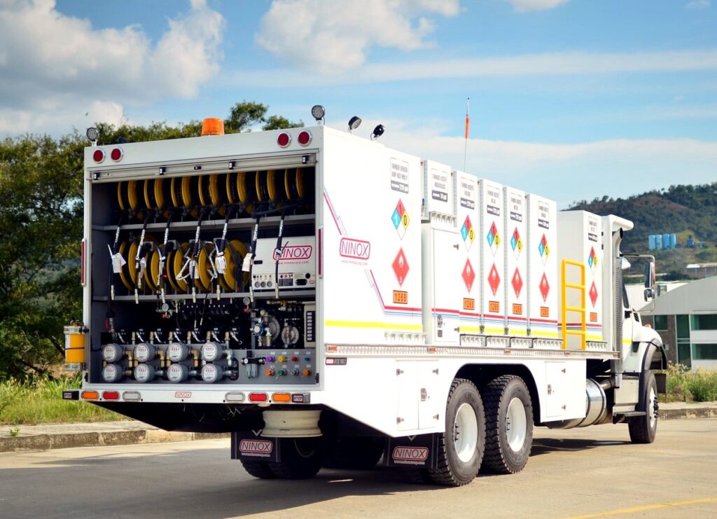MecLube set up of a White mobile lubrication service truck with rear compartment open, showing hose reels, meters, controls, and fluid delivery systems.